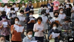 People wearing face masks to help protect against the spread of the coronavirus pray while maintaining social distancing during a service at the Chogyesa temple in Seoul, South Korea, Sunday, Aug. 23, 2020. (AP Photo/Ahn Young-joon)