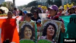 FILE - Activists hold pictures of slain environmental rights activist Berta Caceres during a protest to mark International Women's Day outside the presidential house in Tegucigalpa, Honduras, March 8, 2016.