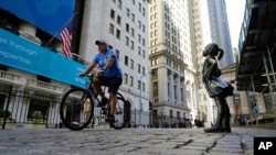 The Fearless Girl statue faces the New York Stock Exchange, June 16, 2021. Stocks got off to a mixed start on Wall Street early Wednesday as traders waited for the latest decision on interest rates from the Federal Reserve. 