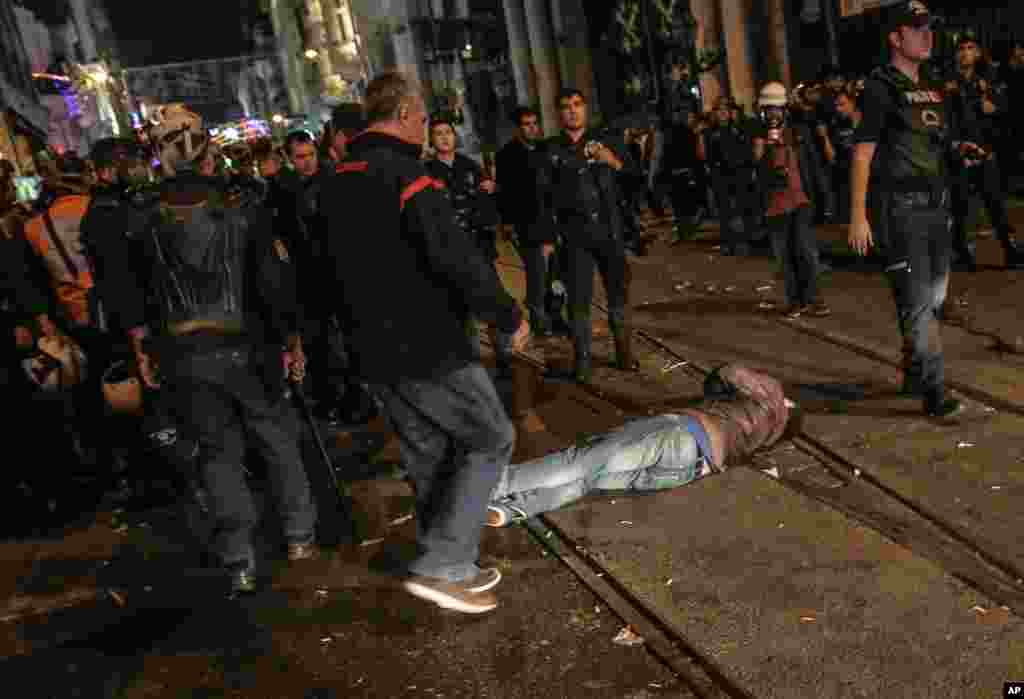 An injured man lies on the ground while Turkish riot police use water cannons and tear gas to disperse protesters in Istanbul, Turkey, Oct. 7, 2014.