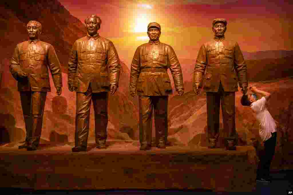 A visitor takes a photo of an exhibit near a statue of Chinese leader Mao Zedong, 2nd from left, and other Communist Party figures at the newly-completed Museum of the Communist Party of China in Beijing.