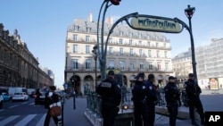 FILE -Police officers stand on patrol at a Metro station outside the Louvre museum near where a soldier opened fire after he was attacked in Paris, Feb. 3, 2017. 