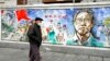 资料照片：在中国中部城市武汉封城76天纪念日前夕，戴着口罩的居民走过一幅名为“记忆”的壁画，武汉是首次发现冠状病毒的地方。(2021年1月22日)