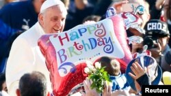 A faithful holds a balloon as Pope Francis, who's 78th birthday is today, arrives to lead his general audience at the Vatican, Dec. 17, 2014. 