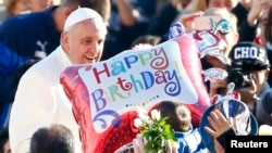 Une fidèle tend un ballon au pape François pour lui présenter des voeux pour le 78ème anniversaire de la naissance du pontif argentin lors d'une audience générale au Vatican, le 17 décembre 2014. 