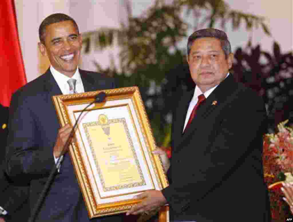 President Barack Obama accepts an award on behalf of his late mother Stanley Ann Dunham for her work in Indonesia, from Indonesian President Susilo Bambang Yudhoyono, during the state dinner at the Istana Negara in Jakarta, Indonesia, Tuesday, Nov. 9, 201