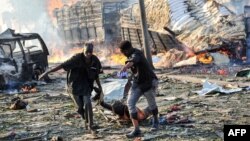 Two men carry the body of a victim following the explosion of a truck bomb in the center of Mogadishu, on Oct. 14, 2017.