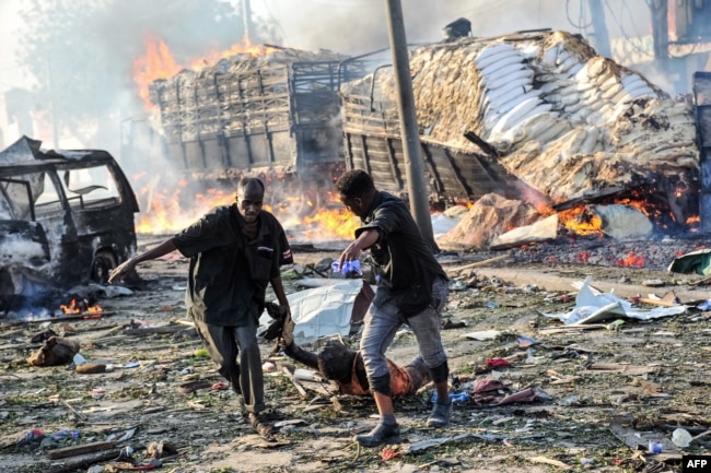 FILE - Two men carry the body of a victim following the explosion of a truck bomb in the center of Mogadishu, Oct. 14, 2017.