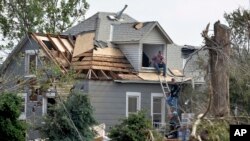 Workers pause while working on house damaged by a tornado in Pilger, Nebraska, June 18, 2014. 
