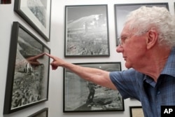 In this June 27, 2019 photo, Gerald Schaber, a former geologist with the U.S. Geological Survey's Astrogeology Science Center, points to a hill on the moon that bears his name in a photograph hanging in his Flagstaff, Ariz., office.