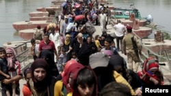 Displaced Sunni people fleeing Ramadi cross a bridge outside Baghdad, May 24, 2015. Iraqi forces recaptured territory from advancing Islamic State militants near the recently fallen city of Ramadi on Sunday.