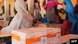 FILE - A handout photo released by the WFP shows women sitting next to WFP-distributed specialized food to combat malnutrition in children at the Pompomari camp in Damaturu on Jan. 26, 2017 during a visit by the WFP executive director.