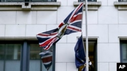 A member of protocol removes the European Union flag from the U.K. Permanent Representation to the EU in Brussels, Jan. 31, 2020.
