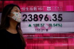 A woman walks past a bank's electronic board showing the Hong Kong share index at Hong Kong Stock Exchange, Oct. 6, 2020.