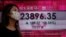 A woman walks past a bank's electronic board showing the Hong Kong share index at Hong Kong Stock Exchange Tuesday, Oct. 6, 2020. Shares advanced in on Tuesday Asia after hopes for economic aid from Washington helped Wall Street recover its losses…