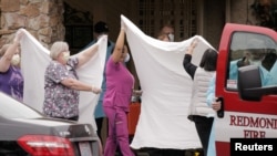 Medics and healthcare workers transfer a patient on a stretcher to an ambulance at the Life Care Center of Kirkland, the long-term care facility linked to the two of three confirmed coronavirus cases in in Kirkland, Washington, March 1, 2020. 