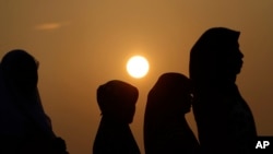 FILE - Indonesian Muslim women walk before Eid al-Fitr prayer that marks the end of the holy fasting month of Ramadan in Jakarta, Indonesia.