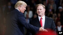 President Donald Trump talks with Republican candidate for Kansas' 2nd Congressional District Steve Watkins during a campaign rally at Kansas Expocentre, Oct. 6, 2018, in Topeka, Kan.