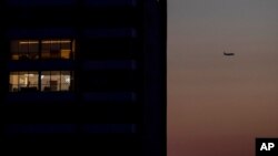 FILE - A passenger plane flies over Beirut, a city shrouded in darkness during a power outage, March 29, 2021. Lebanon has been dealing with electricity cuts for decades.