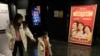 People walk past a poster for the Chinese movie 'Hi, Mom,' which opened on the first day of the Lunar New Year, at a cinema in Beijing, China, Feb. 19, 2021. 