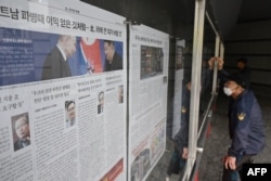 A man reads a newspaper displayed on a street in Seoul, Oct. 21, 2024, showing a photo, left, of North Korean leader Kim Jong Un and Russia's President Vladimir Putin at a banquet in Pyongyang earlier this year.