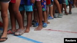 Venezuelan migrant children line up inside a coliseum where a temporary camp has been set up, after fleeing their country due to military operations, according to the Colombian migration agency, in Arauquita, Colombia, March 26, 2021.