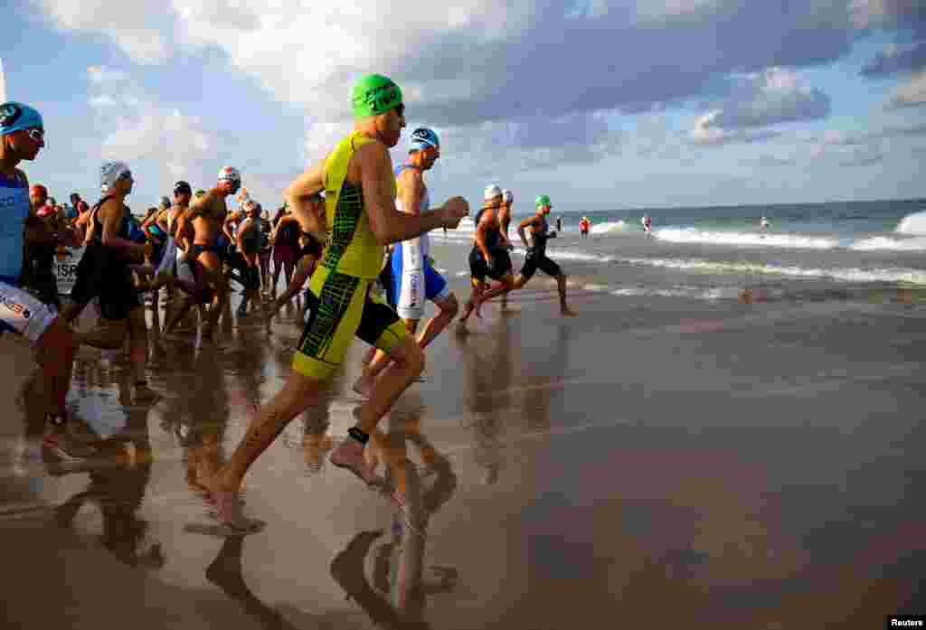 Competitors run into the Mediterranean Sea as they begin the swimming part of a triathlon in Ashdod, Israel.
