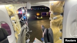 Passenger oxygen masks hang from the roof next to a missing window and a portion of a side wall of an Alaska Airlines Boeing 737 MAX 9 jet in Portland, Oregon, after pilots made an emergency landing on Jan. 5, 2023.