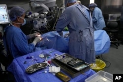 Elias Jaradeh, a legislator and an ophthalmologist, left, performs eye surgery on a man who was injured in the explosion of a handheld device, at a hospital in Beirut, Sept. 20, 2024.