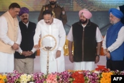 Indian VP Naidu (3L), Union ministers Nitin Gadkari (6L) and Hardeep Singh Puri (5R), Punjab Governor VP Singh Badnore (2L), and other officials stand for the national anthem during the foundation stone-laying ceremony for the planned Dera Baba Nanak-Kartarpur Sahib road corridor to the Pakistan border, at Dera Baba Nanak, Nov. 26, 2018.