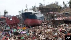 Sebuah kapal tersangkut di atas rumah-rumah yang hancur akibat hantaman topan Haiyan di kota Tacloban, provinsi Leyte, Filipna tengah (10/11).