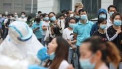 Staff members from the AOC computer monitor factory queue to be tested for the COVID-19 coronavirus in Wuhan, in China's central Hubei province.