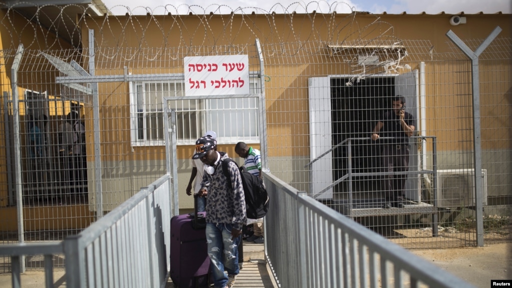 Des migrants africains, munis de bagages, quittent le centre de détention de Holot dans le désert du Néguev, dans le sud d'Israël, le 25 août 2015.