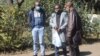 Journalists Samuel Takawira and Frank Chikowore stand with a police detective outside a court in Harare, Zimbabwe, May 23, 2020. (Columbus Mavhunga/VOA) 