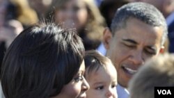 Ibu Negara Michelle Obama dan Presiden Barack Obama menyapa para pendukung saat tiba di bandara Cleveland, Ohio, pada hari Minggu.