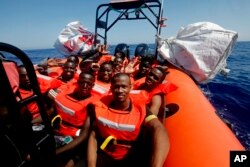 FILE - African migrants wave after being rescued by the MV Geo Barents vessel of MSF, off Libya in the central Mediterranean route, Monday, Sept. 20, 2021.