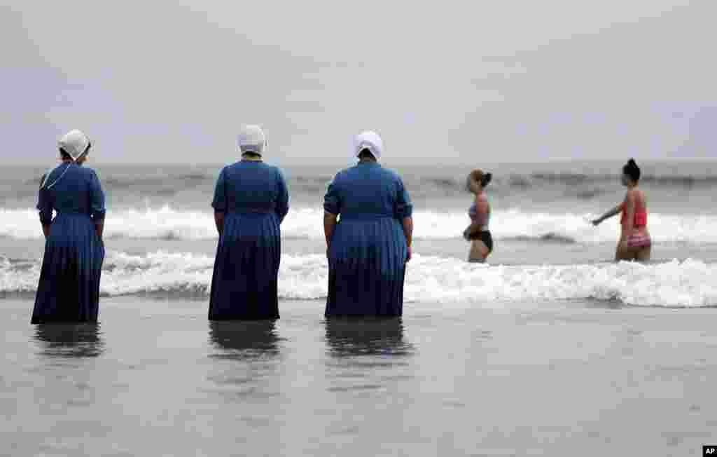 Rosa Graber, third from left, and Margerie, Steury, second from left, Joanne Steury, left, look on as they touch Pacific Ocean waters in Coronado, California, for the first time during a family trip from their Amish community in Michigan, June 9, 2016,