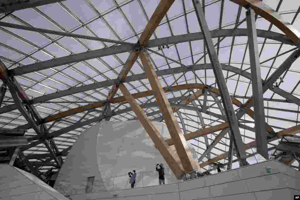 Members of the media take photographs inside the Louis Vuitton Foundation art museum and cultural center, created by American architect Frank Gehry, during the press day, in Paris. The 100-million-euro building, with billowing glass casing and 11 gallery spaces, has been compared to an iceberg or giant sailboat and took over a decade to make.