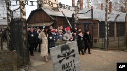 El presidente de Polonia, Andrzej Duda, camina junto a sobrevivientes del campo de concentración nazi de Auschwitz en Osweiecim, Polonia, el lunes, 27 de enero de 2020.