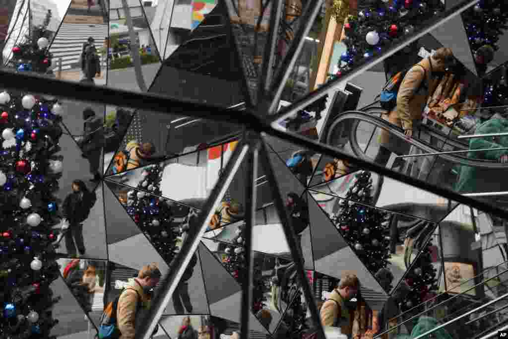 A Christmas tree and shoppers are reflected in the mirrored entrance of a shopping mall at the Harajuku district of Tokyo.