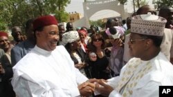 Rival presidential candidates Mahamadou Issoufou, left, and Seini Oumarou greet each other as they cross paths at a polling station in Niamey, Niger, March 12, 2011