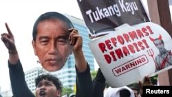 Seorang demonstran mengacungkan potret wajah Presiden Joko Widodo dalam demonstrasi untuk menentang revisi UU Pilkada, di kompleks DPR/MPR, Senayan, Jakarta, Kamis, 22 Agustus 2024. (Foto: Ajeng Dinar Ulfiana/Reuters)