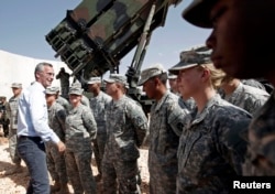 FILE - NATO Secretary General Jens Stoltenberg, second from left, of Norway meets with U.S. soldiers during his visit to view the U.S. Patriot missile system at a Turkish military base in Gaziantep, southeastern Turkey, Oct. 10, 2014.