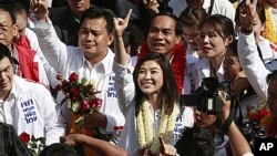 Opposition leader of Phue Thai party, Yingluck Shinawatra, center, flashes a number one sign as she arrives for the registration of constituency candidates competing in upcoming general election in Bangkok, May 24, 2011.