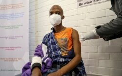 Seorang sukarelawan menerima suntikan dari seorang pekerja medis selama uji klinis manusia pertama di negara itu untuk vaksin potensial melawan virus corona baru, di Soweto. (Foto: Reuters)