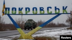 FILE - A military vehicle passes by a road sign that reads 'Pokrovsk’ near a front line in the Donetsk region.