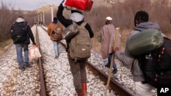 FILE - West African migrants walk on train tracks on their way to the Greek-Macedonian border near the town of Evzonoi, Greece, Feb. 28, 2015.