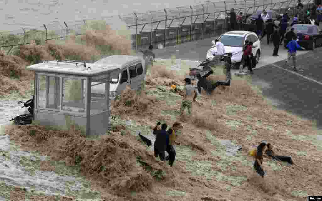 Visitors are hit by a wave caused by a tidal bore which surged past a barrier on the banks of Qiantang River, in Hangzhou, Zhejiang province, China.