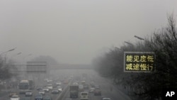 FILE - Vehicles drive along a road with a traffic sign reading "Visibility low, slowdown the speed" on a heavily polluted day in Beijing, Monday, Nov. 30, 2015.
