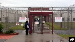 FILE - An employee of Immigration and Customs Enforcement's Stewart Detention Center in Lumpkin, Ga., waits for the front gate to be opened.